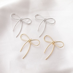 May include: Four gold and silver bow-shaped metal charms with a textured surface. The charms have a loop at the top for attaching to jewellery or other crafts.