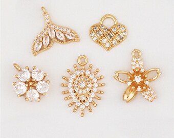 May include: Five gold-tone charms with clear crystal embellishments. The charms include a mermaid tail, a heart, a flower, a sun, and a star.