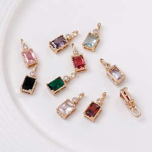 Puede incluir: Surtido de colgantes de charms de tono dorado con piedras preciosas rectangulares de colores. Cada charm tiene un pequeño strass transparente en la parte superior.
