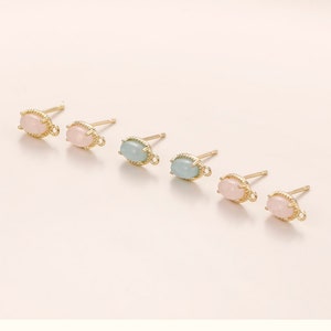 May include: Set of six gold-tone earring findings with oval-shaped pastel pink and light blue stones. The findings have a loop for attaching a dangle charm.
