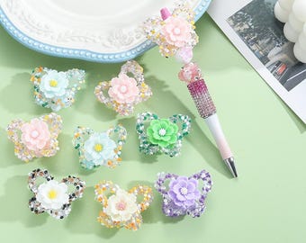 May include: Assortment of ten butterfly-shaped hair clips with rhinestones and colorful flower accents. The clips are arranged on a white surface.