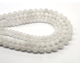 Puede incluir: Una hebra de cuentas redondas blancas hechas de piedra natural. Las cuentas son lisas y pulidas, con una apariencia ligeramente translúcida.