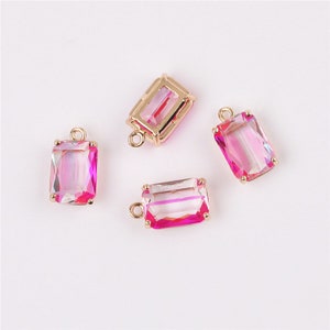 Peut inclure: Quatre breloques pendantes dorées avec des pierres en verre rose et irisé de forme rectangulaire.