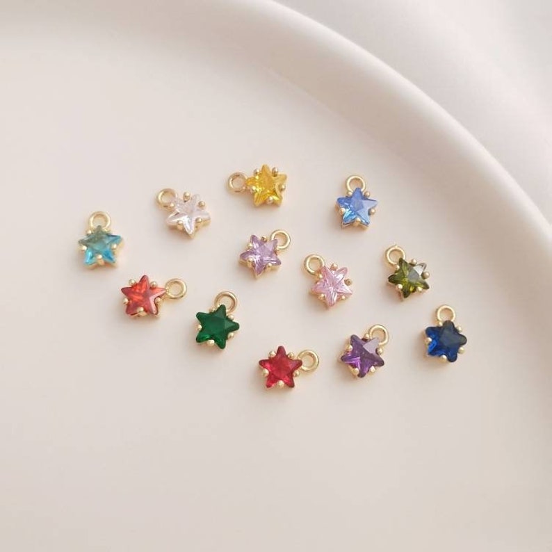 May include: Assortment of 12 gold star charms with different colored crystals. The charms are perfect for jewelry making, scrapbooking, and other craft projects.