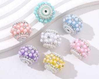 May include: A collection of seven colorful, decorative beads. Each bead is a different pastel color, including pink, blue, purple, and yellow. The beads are adorned with faux pearls and rhinestones, creating a glamorous look.