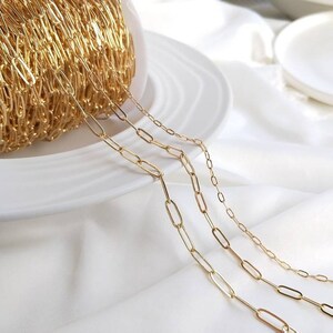 May include: Three gold chain necklaces with oval links. The chains are arranged in order of size, with the largest chain at the top and the smallest chain at the bottom.