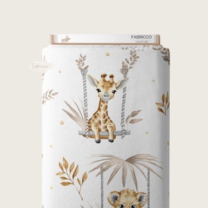 May include: White fabric with a repeating pattern of a giraffe and a lion on a swing, surrounded by brown leaves and gold dots. The text "Fabricco Loved by Kids" is at the top of the image.