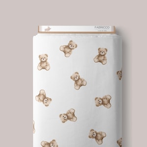 May include: White fabric with a repeating pattern of brown teddy bears. The fabric has the text "Fabricco Loved by Kids" printed on a label.