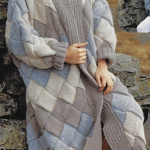 May include: A long, knitted cardigan with a geometric pattern in shades of blue, beige, and gray. The cardigan has a shawl collar and a loose fit.