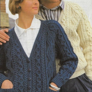 May include: A couple wearing matching cable knit cardigans. The woman is wearing a blue cardigan with buttons and pockets. The man is wearing a cream cardigan.