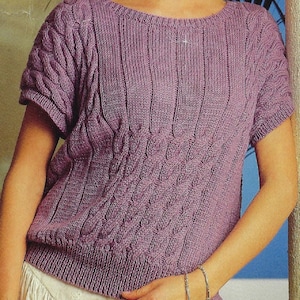 May include: A purple knitted sweater with a cable knit pattern and short sleeves.