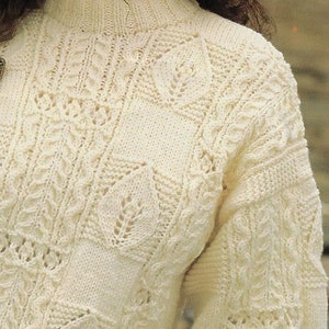 May include: A white knitted sweater with a delicate cable knit pattern and a high neckline.