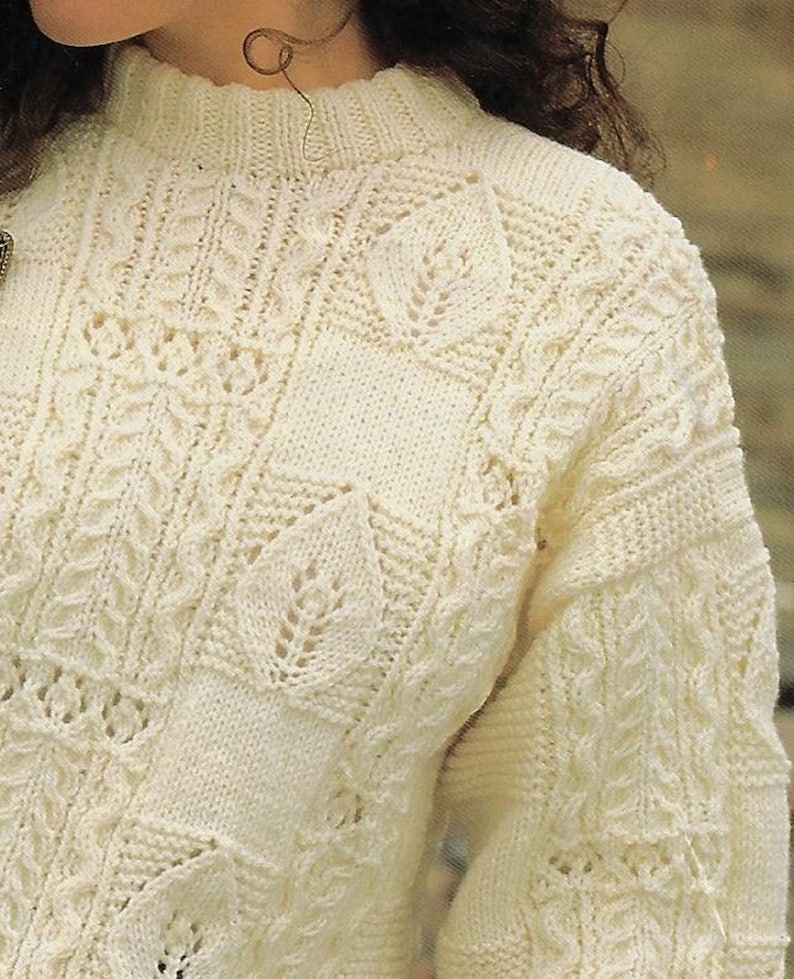 K&ouml;nnte beinhalten: Ein wei&szlig;er Strickpullover mit einem zarten Zopfmuster und einem hohen Kragen.