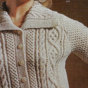 Puede incluir: Un cárdigan de punto de color crema con cierre de botones y un patrón de punto de cable. El cárdigan tiene cuello y mangas largas.