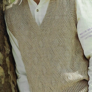 以下が含まれることがあります： Vネックとテクスチャードパターンが付いたベージュのニットベスト。ベストは白いボタンダウンシャツの上に着用されています。