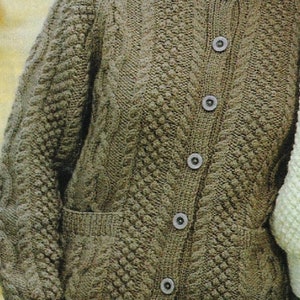 Puede incluir: Un cárdigan de punto marrón con un patrón de punto de cable y seis botones en la parte delantera. El cárdigan tiene dos bolsillos de parche en la parte delantera.