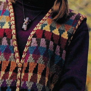 May include: A multi-coloured knitted waistcoat with a button fastening. The waistcoat has a geometric pattern in shades of brown, red, purple, blue and beige. The waistcoat is worn over a purple turtleneck.