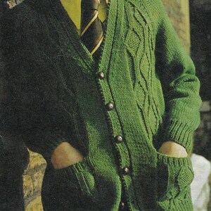 May include: A green knitted cardigan with a cable knit pattern, a v-neck, and button closure. The cardigan has two pockets and is worn over a yellow collared shirt with a dark striped tie.