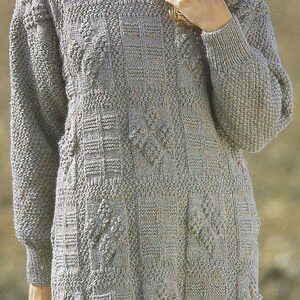 K&ouml;nnte beinhalten: Ein grauer Strickpullover mit einem strukturierten Muster. Der Pullover hat lange &Auml;rmel und einen runden Ausschnitt.