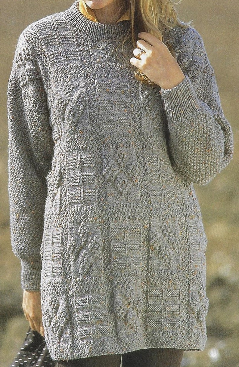 K&ouml;nnte beinhalten: Ein grauer Strickpullover mit einem strukturierten Muster. Der Pullover hat lange &Auml;rmel und einen runden Ausschnitt.