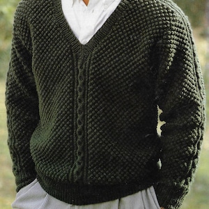 May include: A dark green knitted sweater with a v-neck and a cable knit pattern.