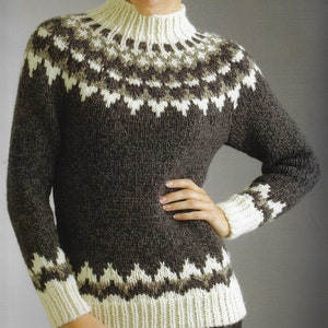 May include: A dark brown knit sweater with a high, cream-colored collar and cuffs. The sweater features a geometric pattern in cream and light brown around the yoke and cuffs. The sweater has long sleeves.