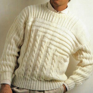 May include: A white knitted sweater with a cable knit pattern. The sweater has a crew neck and long sleeves.