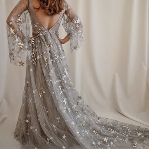 May include: A gray tulle gown with a long train, featuring a scattered pattern of gold and white stars.