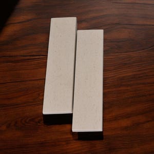 May include: Two off-white rectangular drawer pulls with a speckled finish.