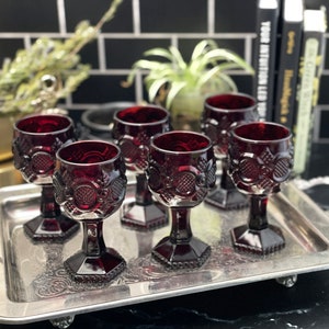 May include: Set of six ruby red glass goblets with a textured design, arranged on a silver tray.