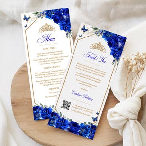 Könnte beinhalten: Elegante Hochzeitsmenü- und Dankeskarten. Die Karten haben einen weißen Hintergrund mit einem goldenen Rand, ein königsblaues Blumendesign und eine goldene Tiara. Die Menükarte listet Vorspeisen, Hauptgerichte und Desserts auf.