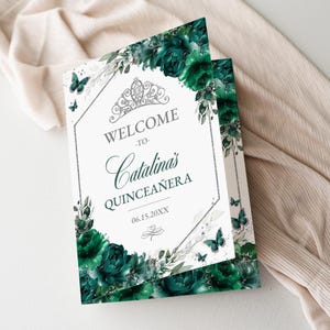 May include: A white invitation with the text "WELCOME to Catalina's QUINCEAÑERA" surrounded by dark green floral and butterfly illustrations. A silver tiara and decorative border complete the design.