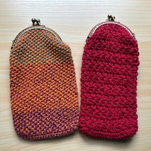 May include: Two handmade crochet coin purses. One is a gradient of orange, purple, and teal. The other is a solid red. Both have a metal clasp closure. These small pouches are perfect for carrying coins, small items, or as a unique gift.