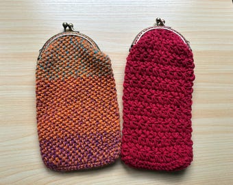 May include: Two handmade crochet coin purses. One is a gradient of orange, purple, and teal. The other is a solid red. Both have a metal clasp closure. These small pouches are perfect for carrying coins, small items, or as a unique gift.