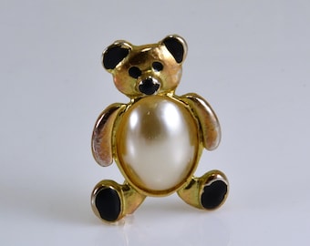 Könnte beinhalten: Eine goldfarbene Teddybär-Brosche mit schwarzen Akzenten und einer weißen Perle in der Mitte.