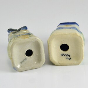 May include: Two ceramic salt and pepper shakers with a blue and white design. The shakers are shaped like people and have a hole in the bottom for filling. The bottom of the shakers are marked "JAPAN".