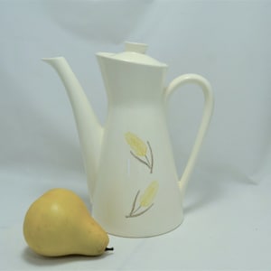 May include: White ceramic coffee pot with a yellow and brown floral design. The pot has a tall, slender shape and a spout on the side.