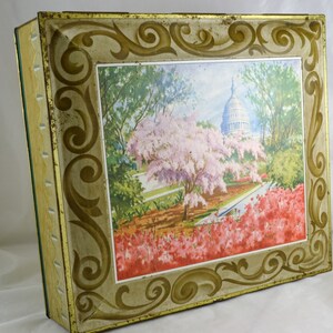 K&ouml;nnte beinhalten: Vintage Blechdose mit einem goldenen und wei&szlig;en verzierten Rahmen und einem farbenfrohen Bild des US-Kapitols mit Kirschbl&uuml;ten und Azaleen in voller Bl&uuml;te.