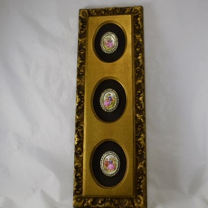 May include: A gold-framed wall decor with three round, black-backed, framed images of couples in vintage clothing. The images are set against a white background.