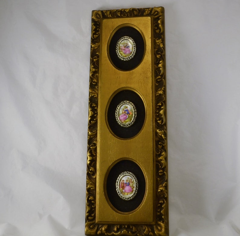 May include: A gold-framed wall decor with three round, black-backed, framed images of couples in vintage clothing. The images are set against a white background.