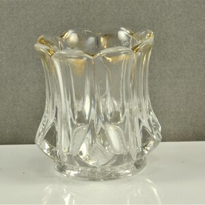 May include: A clear glass bud vase with a gold rim and a faceted design. The vase is approximately 3 inches tall.