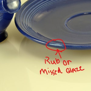 May include: A close-up of a blue ceramic plate with a slight imperfection on the rim, possibly a rub or missed glaze.