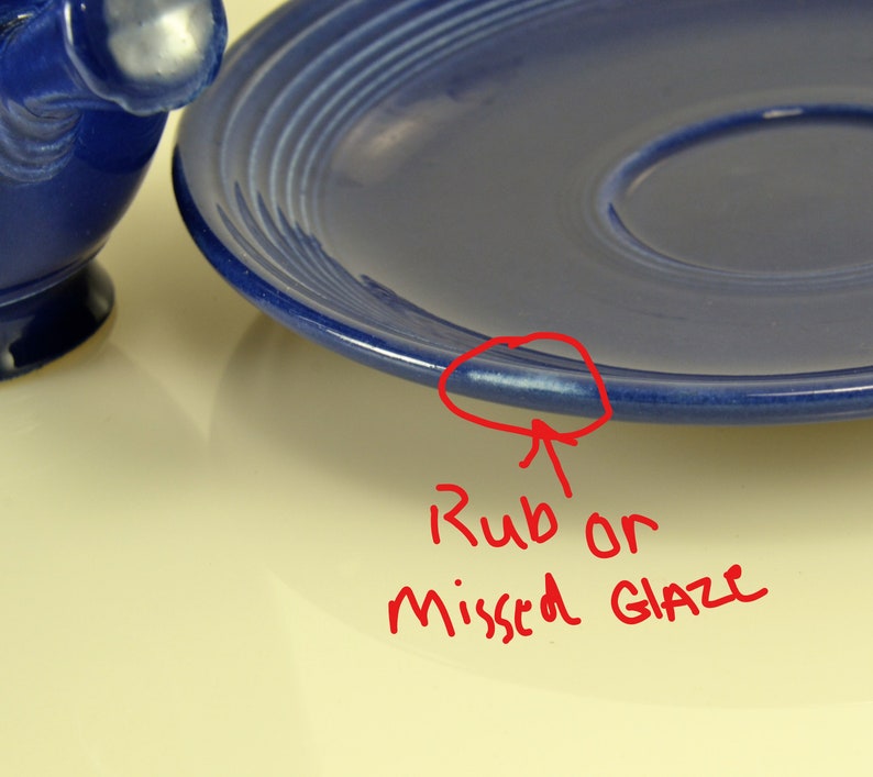 May include: A close-up of a blue ceramic plate with a slight imperfection on the rim, possibly a rub or missed glaze.
