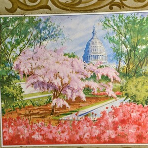 K&ouml;nnte beinhalten: Eine Vintage-Dose mit einem gemalten Bild des US-Kapitolgeb&auml;udes in Washington, D.C. Das Geb&auml;ude ist von B&auml;umen und bl&uuml;henden Blumen umgeben, darunter rosa Kirschbl&uuml;ten und rote Azaleen.