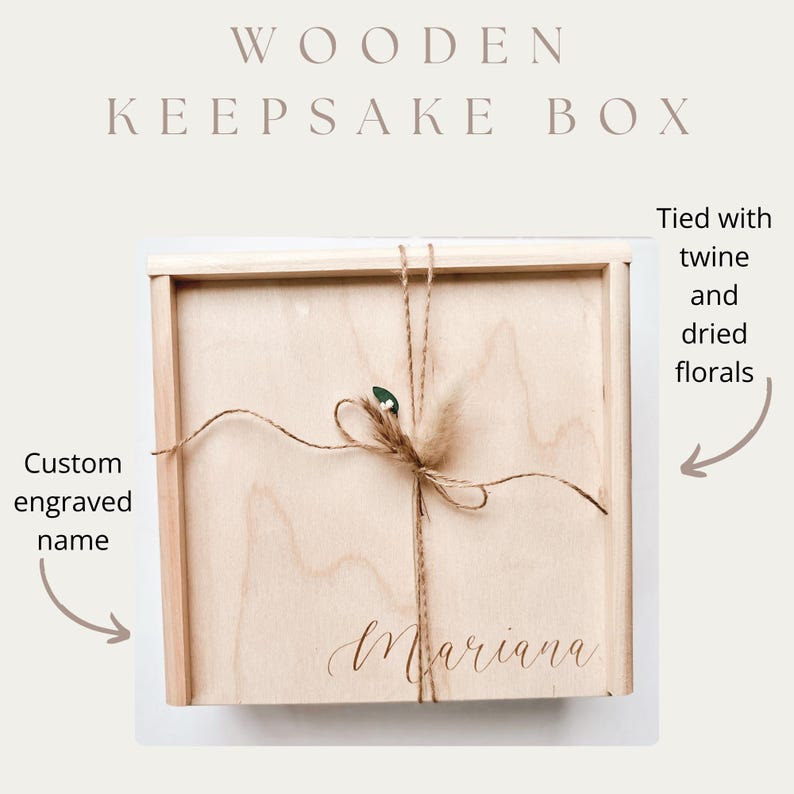 May include: A wooden keepsake box with a light wood finish. The box is tied with twine and dried florals. The name "Mariana" is custom engraved on the front. The text "WOODEN KEEPSAKE BOX" is at the top.