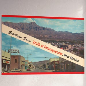 May include: A vintage-style poster featuring a scenic view of Truth or Consequences, New Mexico, with a mountain range in the background. The poster has a red border and a diagonal banner with the text "Greetings From Truth or Consequences, New Mexico."