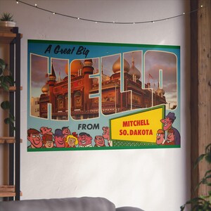 Könnte beinhalten: Ein Posterdruck im Vintage-Stil mit dem Wort "HELLO" in großen Buchstaben, der ein Gebäude mit goldenen Kuppeln zeigt. Die Postkarte lautet "A Great Big HELLO from Mitchell So. Dakota" mit Cartoon-Charakteren. Der Druck hat einen türkisfarbenen Rand.