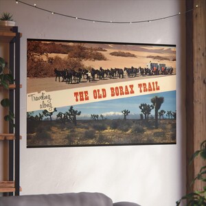 Può includere: Una cartolina vintage con una foto in bianco e nero di un convoglio di muli che viaggia lungo l'Old Borax Trail. La cartolina ha un cielo blu con nuvole bianche e un paesaggio desertico sullo sfondo. Il testo sulla cartolina recita "Traveling along THE OLD BORAX TRAIL".