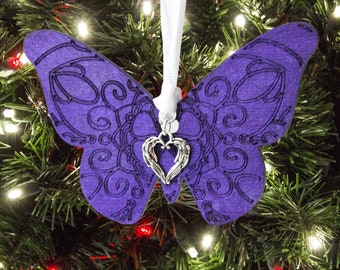 May include: Purple butterfly Christmas bauble with a silver heart charm with wings. The bauble is hanging on a Christmas tree.