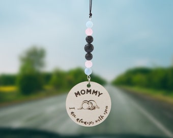 May include: A wooden car charm with the text "Mommy I am always with you" and a small image of a mother and child. The charm is attached to a string of black lava beads, pink and blue beads.